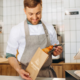 Boulanger emballe croissant dans un sachet kraft personnalisé