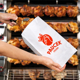 Personne emballe un poulet dans un sac en papier personnalisé dans une rôtisserie